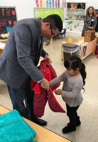 Assemblyman Rudy Salas and a young constituent try on a winter coat. 